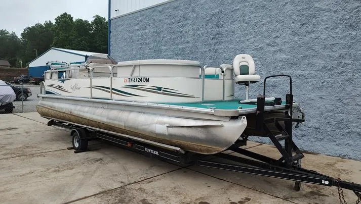 Slide: The Image of 2006 SunChaser 825F pontoon boat on trailer, parked outdoors near a blue wall. - 9