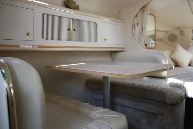 Slide: The Image of Interior of 2000 Sea Ray 290 Sundancer, featuring a cozy dining area with cushioned seating. - 10
