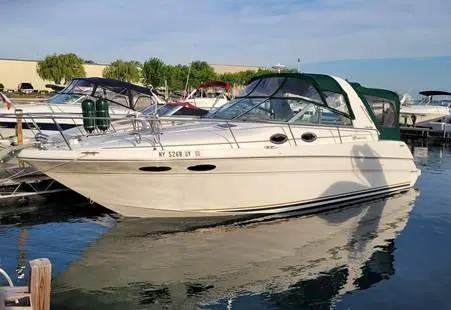 Slide: The Image of 2000 Sea Ray 290 Sundancer boat docked in a marina, featuring a sleek white design. - 2