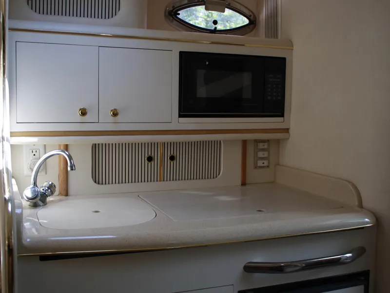 Slide: The Image of 2000 Sea Ray 290 Sundancer galley with sink, microwave, and storage cabinets. - 8