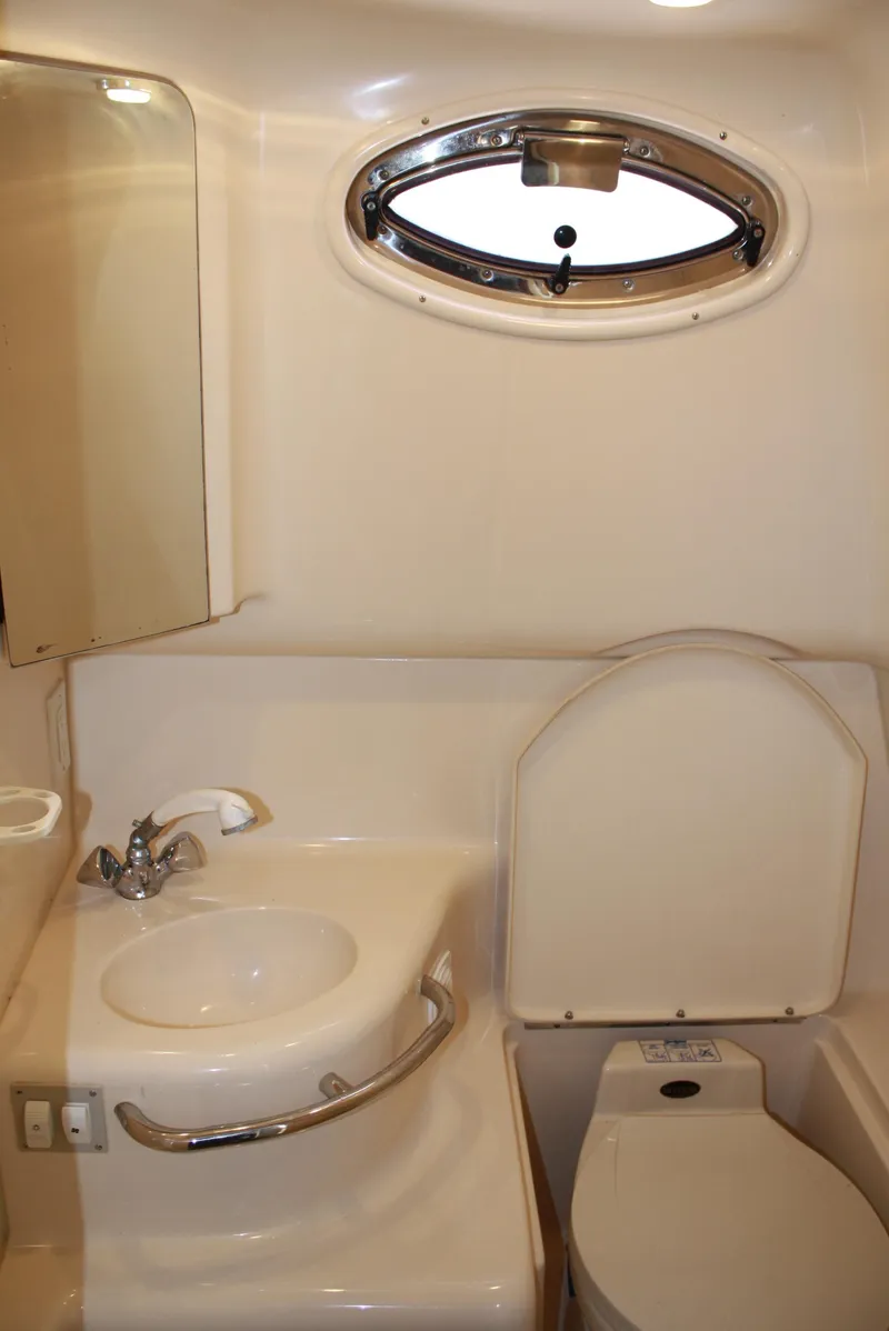 Slide: The Image of 2000 Sea Ray 290 Sundancer bathroom with sink, toilet, and porthole window. - 9