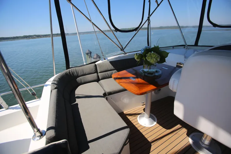 Slide: The Image of 2007 Beneteau Swift Trawler 42 interior with cushioned seating and wooden table, overlooking serene waters. - 13