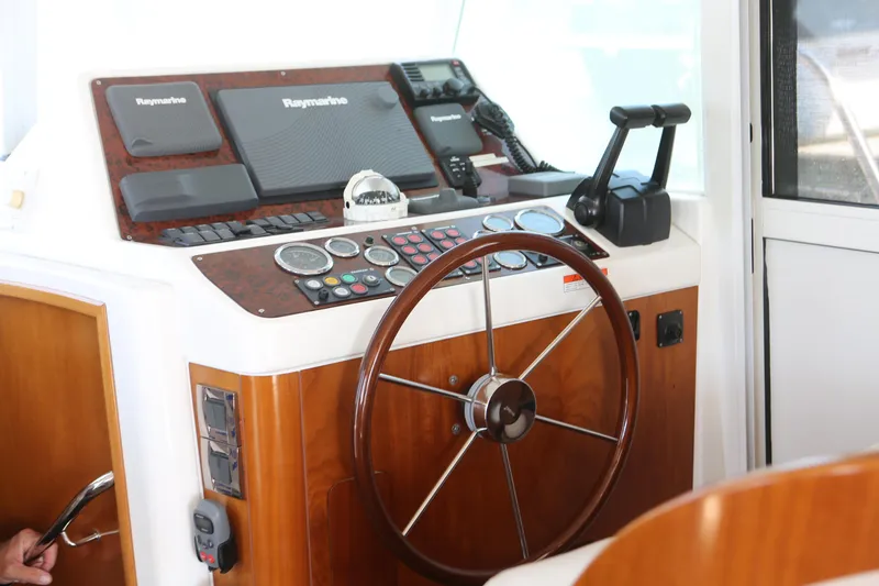 Slide: The Image of 2007 Beneteau Swift Trawler 42 helm with wooden steering wheel and navigation instruments. - 18