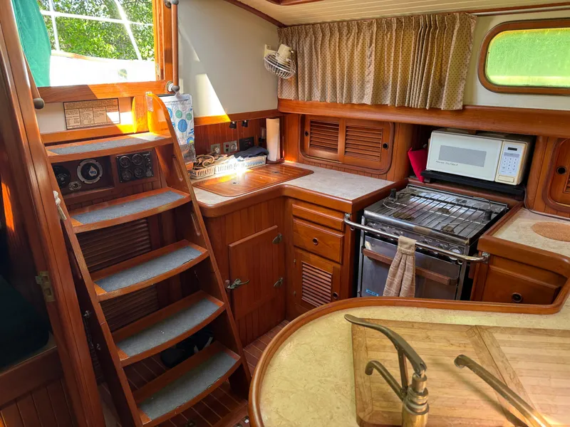Slide: The Image of Interior of 1987 Hans Christian Christina 40 sailboat, featuring a cozy kitchen with wooden cabinetry. - 6