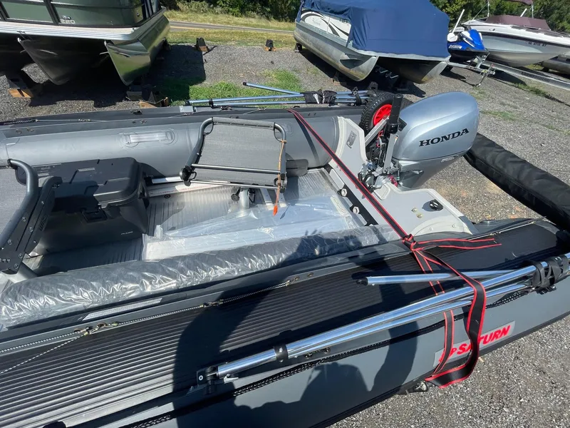 Slide: The Image of Inflatable Saturn HD430 boat with Honda motor, parked on gravel, surrounded by other boats. - 7