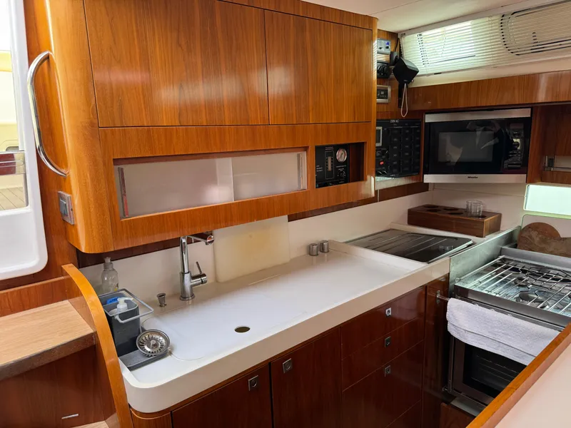 Slide: The Image of Luxurious Amel 55 yacht kitchen interior with modern appliances and wooden cabinetry, 2012 model. - 9