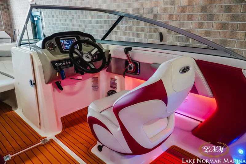 Slide: The Image of 2018 Chaparral 21 Surf boat interior with red and white seating, modern dashboard, and ambient lighting. - 12
