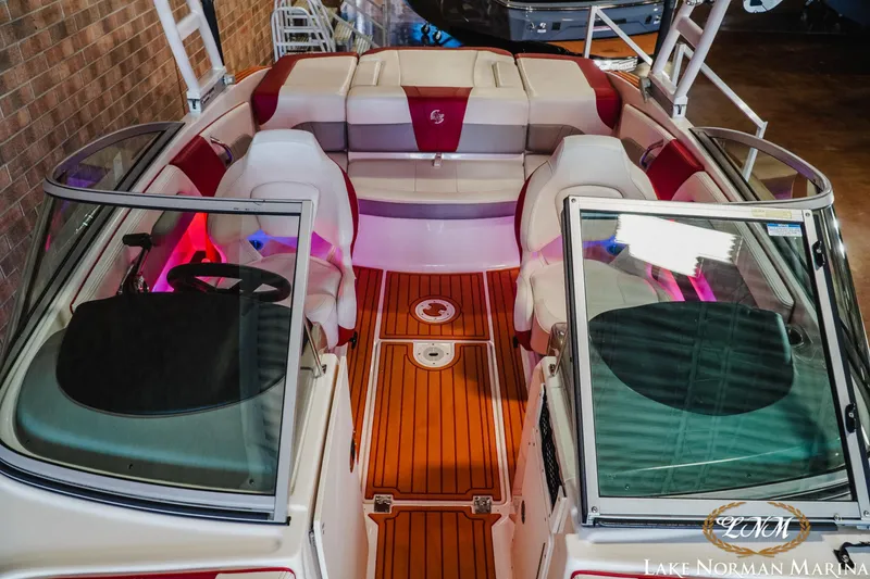 Slide: The Image of 2018 Chaparral 21 Surf boat interior with red and white seating, wooden flooring. - 17