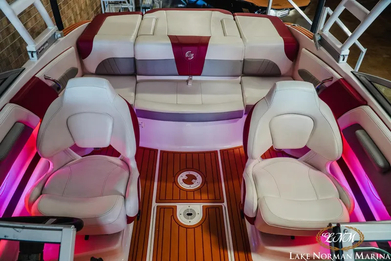Slide: The Image of 2018 Chaparral 21 Surf boat interior with white and red seating, wood flooring, and ambient lighting. - 18