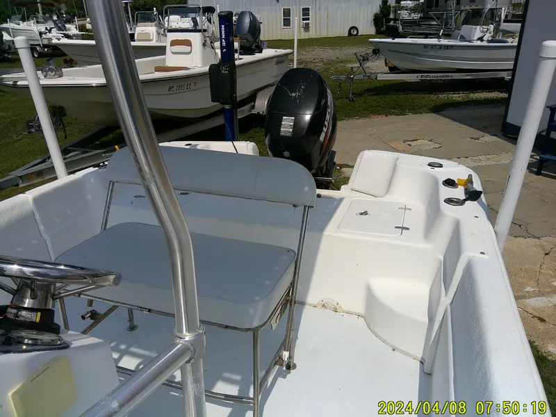 Slide: The Image of 2010 Carolina Skiff 198 DLV boat interior with seating and motor, docked outdoors. - 10