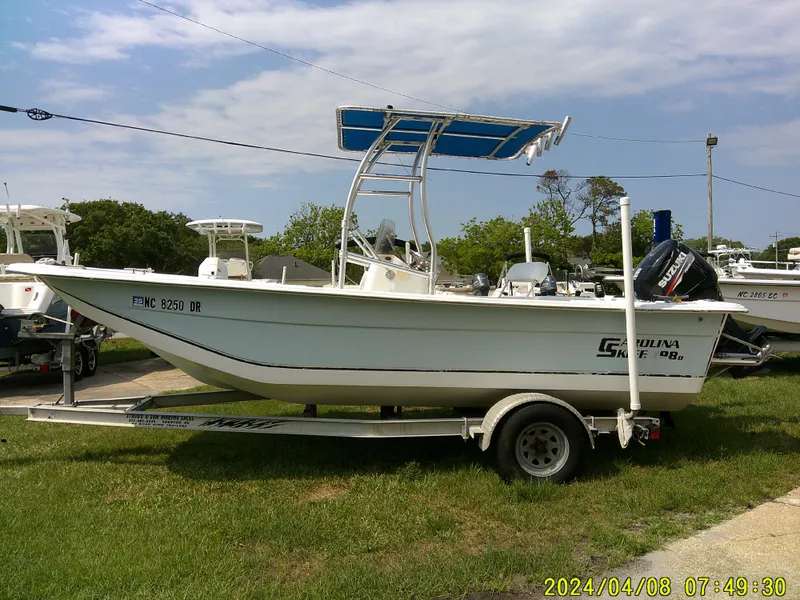 Slide: The Image of 2010 Carolina Skiff 198 DLV boat on trailer, parked outdoors under a clear sky. - 4