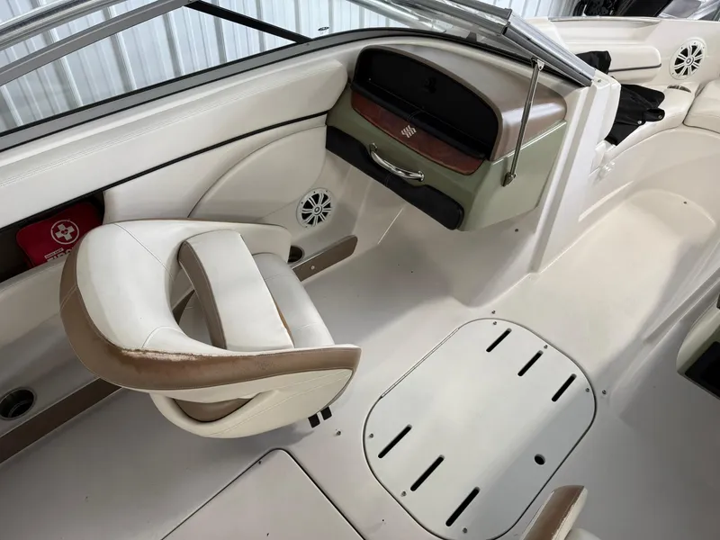 Slide: The Image of 2009 Four Winns H200 boat interior with white and beige seating, dashboard, and storage compartments. - 11