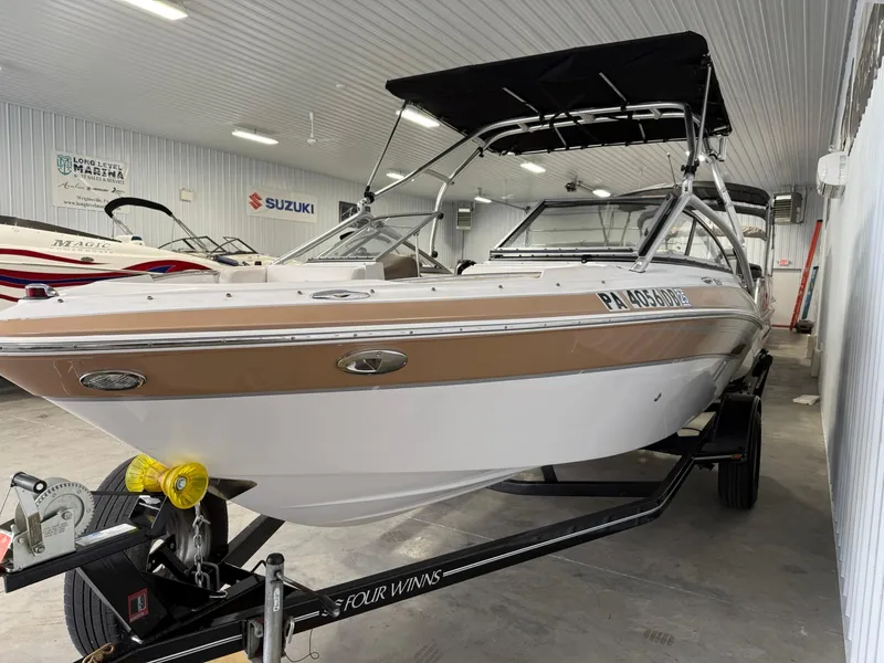 Slide: The Image of 2009 Four Winns H200 boat in showroom, featuring sleek design and black canopy. - 4