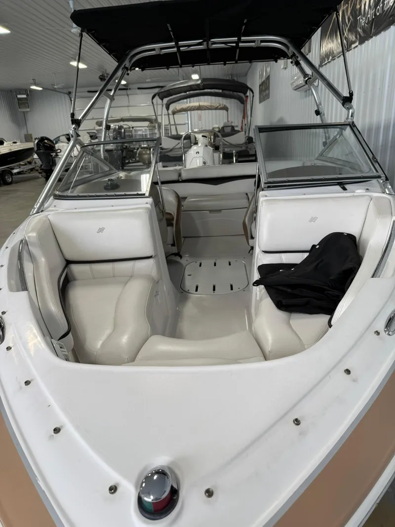 Slide: The Image of 2009 Four Winns H200 boat with white interior and black canopy in a showroom. - 5