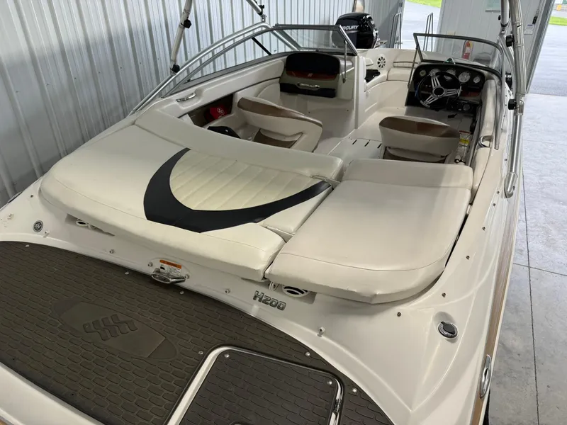 Slide: The Image of 2009 Four Winns H200 boat interior with white seating and dashboard in a storage facility. - 7