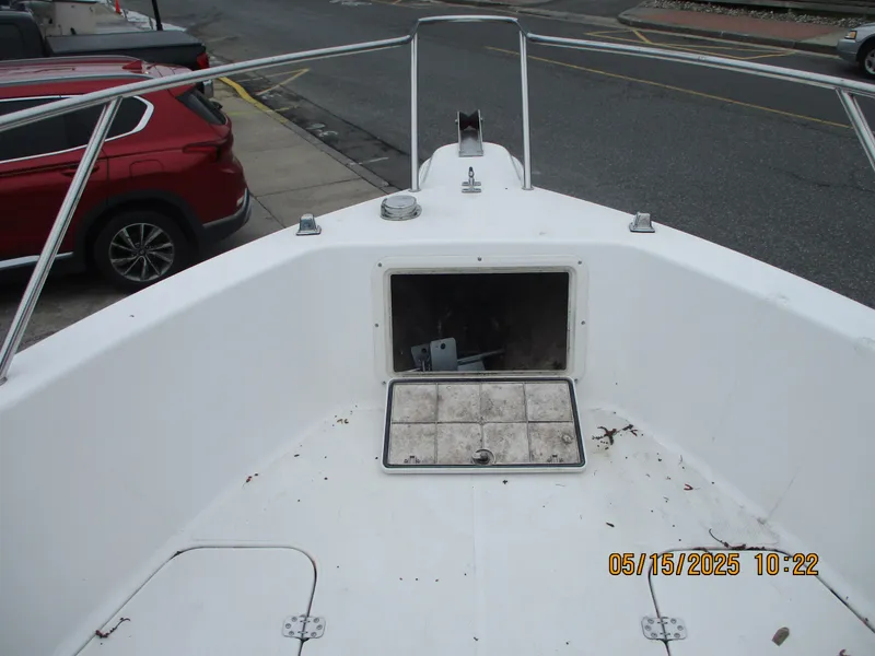 Slide: The Image of 1995 Wellcraft 218ccf boat bow with open storage compartment, docked near a red car. - 15