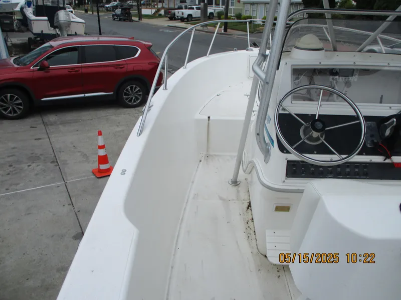 Slide: The Image of 1995 Wellcraft 218ccf boat docked, featuring steering wheel and console, with red SUV nearby. - 8