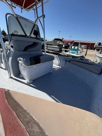 Slide: The Image of 2004 Blue Wave 22STL boat interior with seating and storage, docked under clear blue sky. - 5