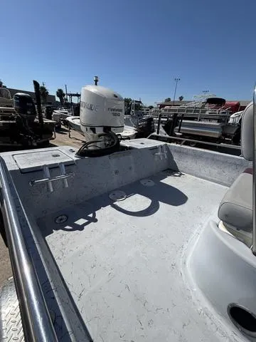 Slide: The Image of 2004 Blue Wave 22STL boat interior with motor, parked outdoors under clear sky. - 6