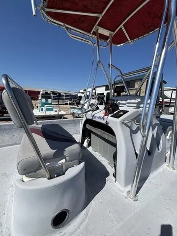 Slide: The Image of 2004 Blue Wave 22STL boat with red canopy and seating, docked under clear blue sky. - 7