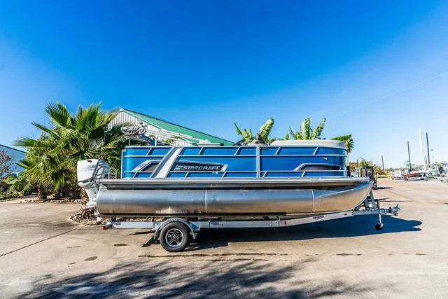 Slide: The Image of 2025 Starcraft EX20FD pontoon boat on trailer, parked outdoors under clear blue sky. - 1