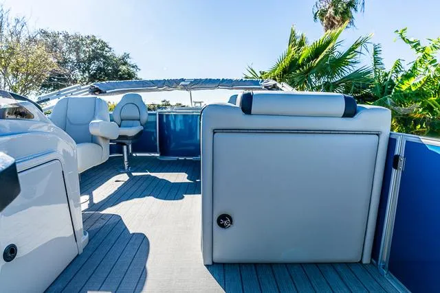 Slide: The Image of 2025 Starcraft EX20FD boat interior with seating, open deck, and lush greenery background. - 5