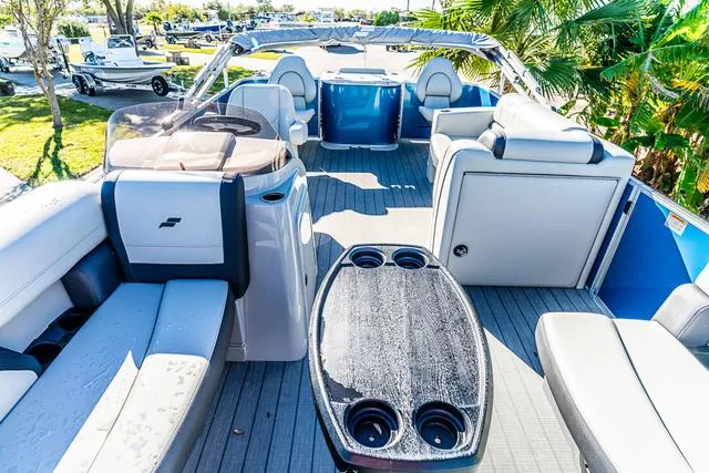 Slide: The Image of 2025 Starcraft EX20FD boat interior with seating, table, and helm, surrounded by lush greenery. - 9