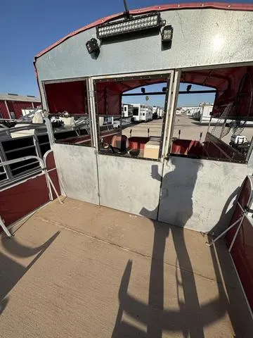 Slide: The Image of 1999 Landau 20 boat with red canopy and metal frame, docked in a marina. - 4