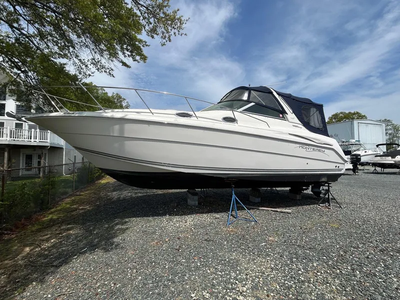 Slide: The Image of 2003 Monterey 302 Cruiser boat on gravel lot under blue sky. - 1