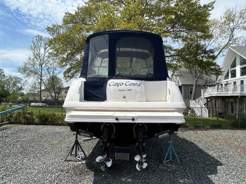 Slide: The Image of 2003 Monterey 302 Cruiser boat on stands, rear view, outdoors, with trees and houses in background. - 3