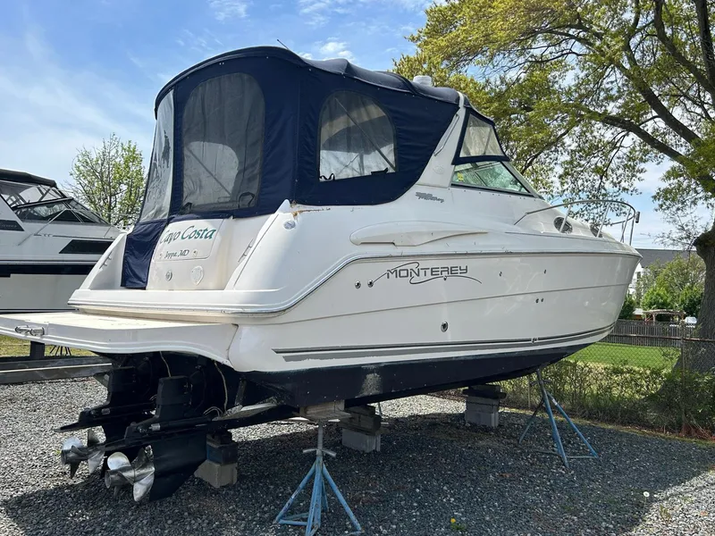 Slide: The Image of 2003 Monterey 302 Cruiser boat on stands, with blue canopy, parked outdoors. - 4
