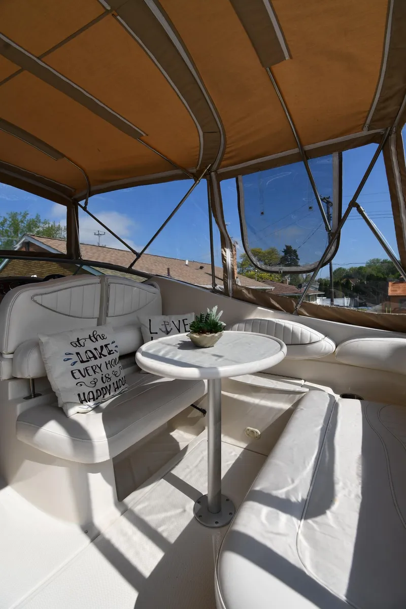 Slide: The Image of 2000 Maxum 2700 SCR boat interior with white seating, table, and decorative pillows. - 20