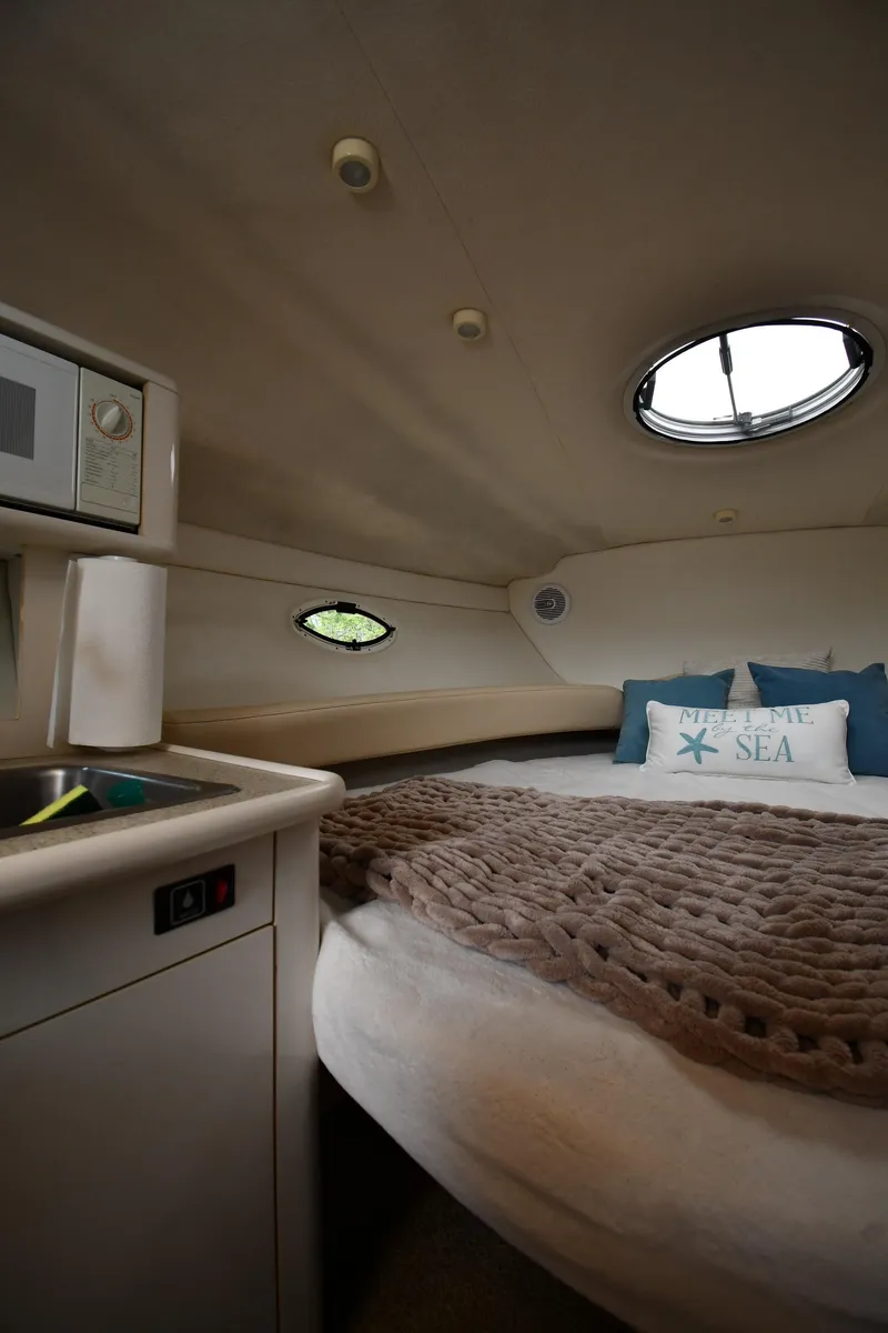 Slide: The Image of 2000 Maxum 2700 SCR cabin interior with cozy bed, microwave, and porthole windows. - 28