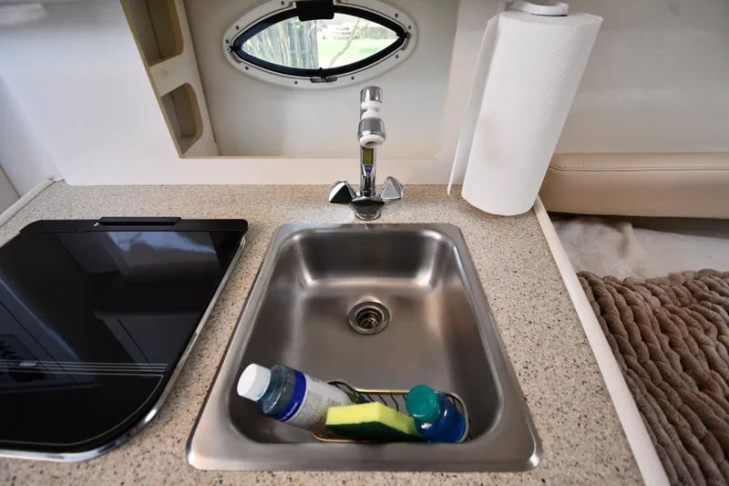 Slide: The Image of Compact kitchen sink area in 2000 Maxum 2700 SCR boat with faucet and cleaning supplies. - 35