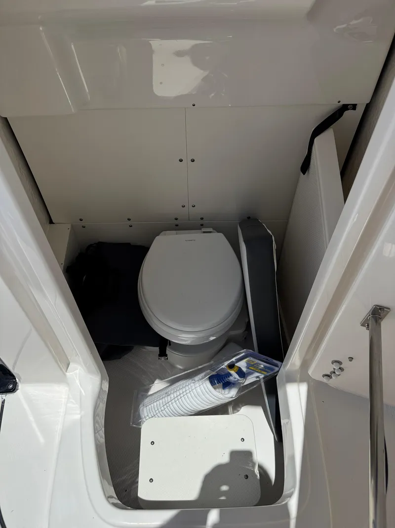 Slide: The Image of 2025 Robalo R270 Center Console boat interior with compact marine toilet. - 30
