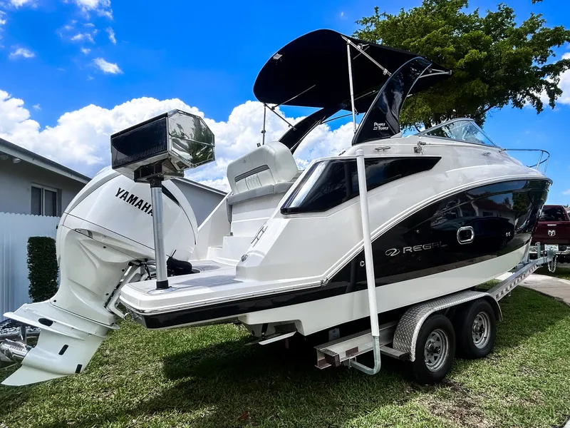 Slide: The Image of 2023 Regal 26 XO boat on trailer with Yamaha outboard motor, parked on grass. - 1