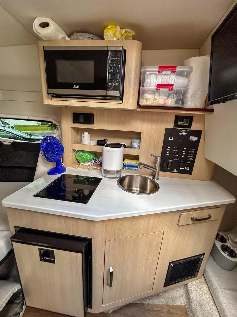 Slide: The Image of Compact kitchen area in 2023 Regal 26 XO boat with microwave, sink, and storage. - 12
