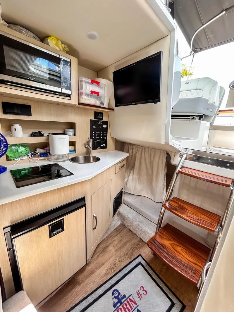 Slide: The Image of Interior of 2023 Regal 26 XO boat with kitchenette, TV, and stairs. - 17