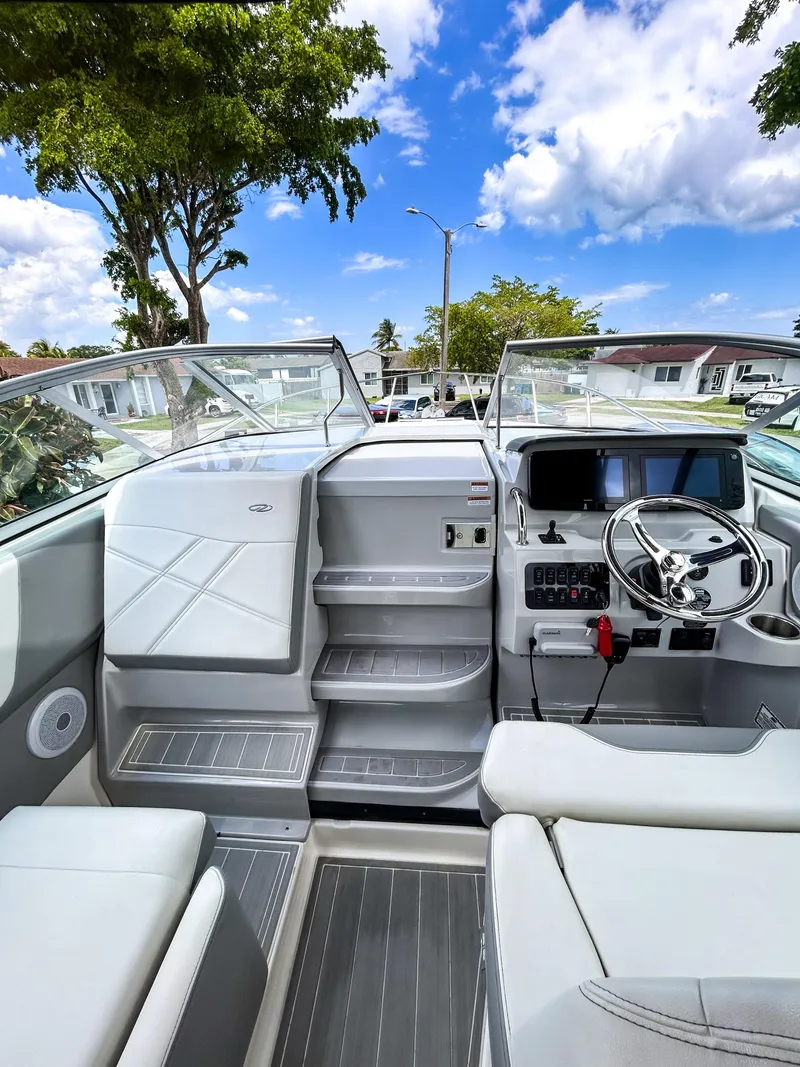 Slide: The Image of 2023 Regal 26 XO boat interior with modern dashboard and seating under a clear blue sky. - 9