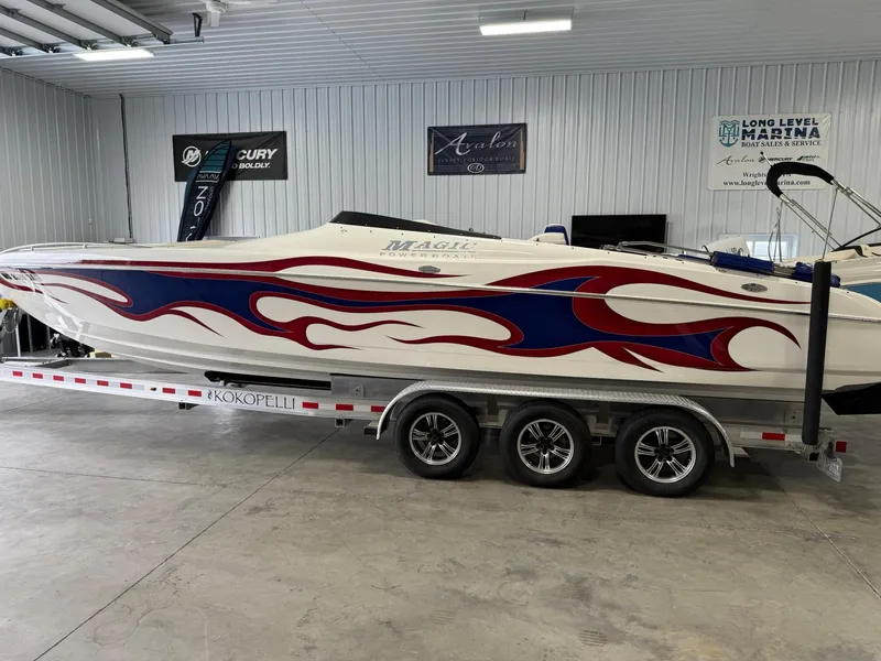 Slide: The Image of 2006 Magic 29 Wizard boat with red and blue flame design on a trailer in a garage. - 1