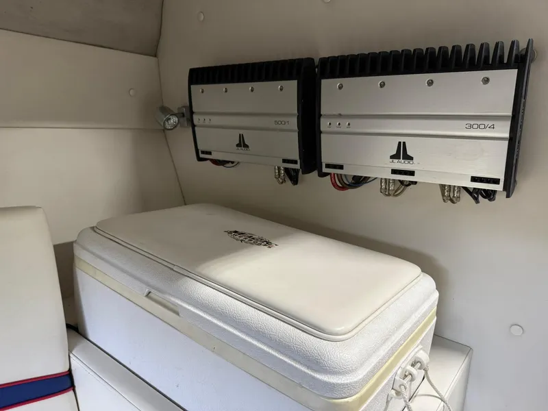 Slide: The Image of Audio amplifiers and cooler inside a 2006 Magic 29 Wizard boat cabin. - 24