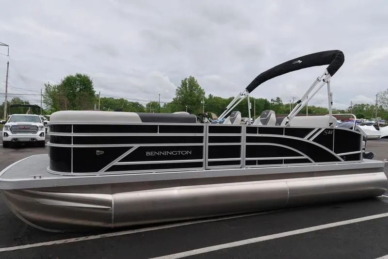 Slide: The Image of 2025 Bennington S Swingback 22 SSB Limited pontoon boat in a parking lot. - 2