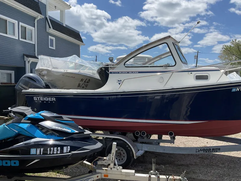 Slide: The Image of 2015 Steiger Craft 21 DV Block Island boat on trailer, parked beside a blue Sea-Doo. - 5