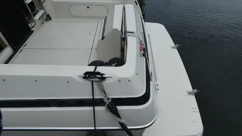 Slide: The Image of 1996 Bayliner 3488 Avanti Command Bridge boat docked, showing rear deck and water. - 27