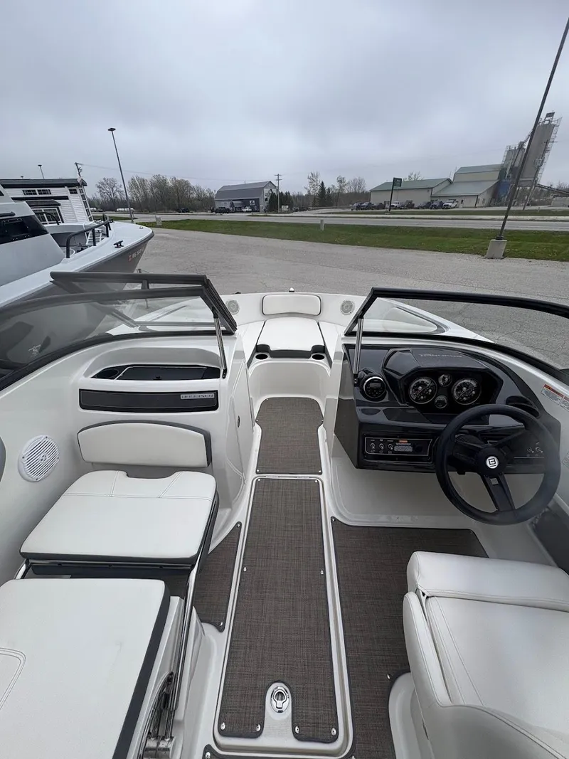Slide: The Image of 2017 Bayliner VR5 Bowrider interior with steering wheel and seating, docked outdoors. - 5