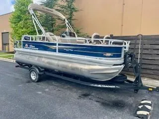 Slide: The Image of 2023 Sun Tracker Bass Buggy 18 DLX pontoon boat on trailer, parked outdoors. - 5