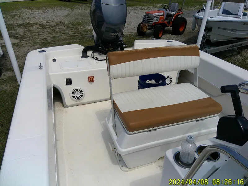 Slide: The Image of 2015 Sundance B22CCR boat interior with seating and motor, parked near a tractor. - 13