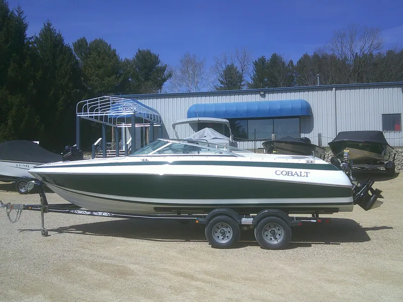 The Image of 1998 Cobalt 220 boat on trailer, parked outdoors near a building. - 1