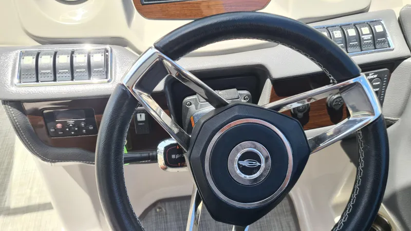Slide: The Image of Steering wheel of a 2018 Chaparral Suncoast 250 Deluxe boat, featuring control switches. - 16