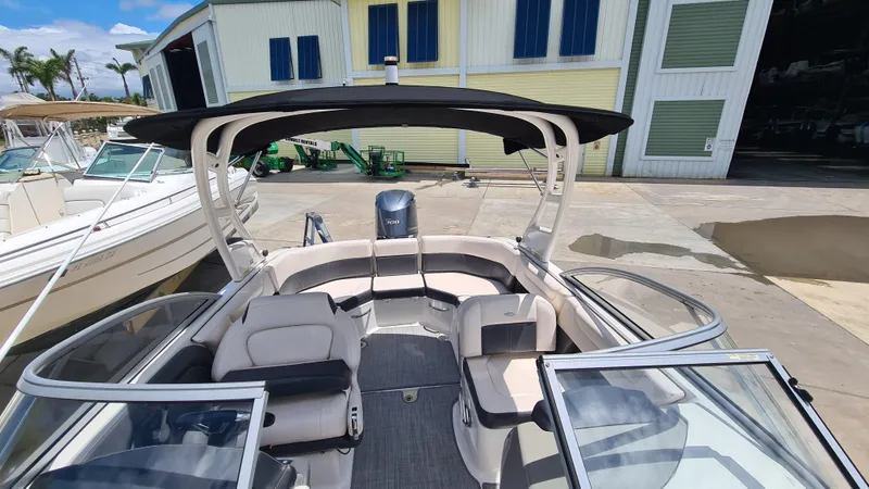 Slide: The Image of 2018 Chaparral Suncoast 250 Deluxe boat with spacious seating and canopy, docked near a marina. - 9